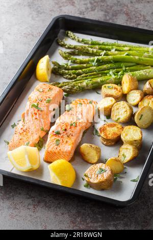 Aliments sains filet de saumon cuit avec asperges et pommes de terre dans une plaque de cuisson sur la table. Verticale Banque D'Images