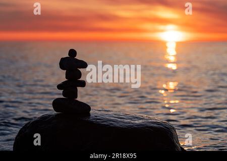 Pyramides en pierre sur la plage de sable de la mer Baltique à Rügen jusqu'au spectaculaire coucher de soleil orange Banque D'Images