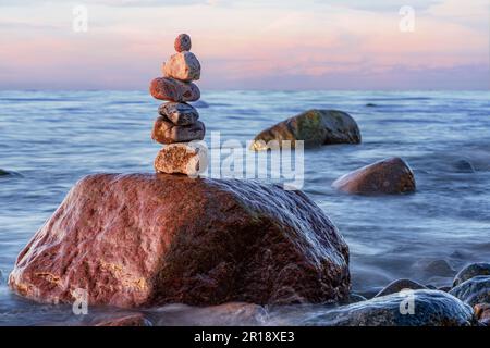 Pyramides en pierre sur la plage de sable de la mer Baltique à Rügen jusqu'au spectaculaire coucher de soleil orange Banque D'Images