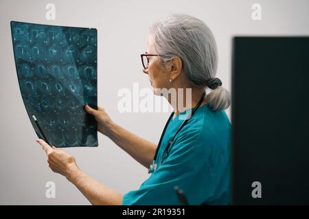 Une femme diagnosticienne expérimentée examine une IRM du cerveau Banque D'Images