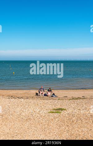 Un couple qui profite d'une journée ensoleillée sur une plage à Whitstable, Kent, Angleterre Banque D'Images