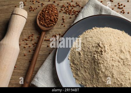 Assiette avec farine de sarrasin, grains et rollPIN sur table en bois Banque D'Images