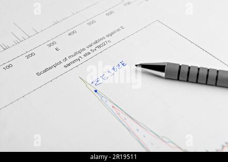 Papier avec diagramme de dispersion imprimé, calculs mathématiques écrits et stylo, gros plan Banque D'Images