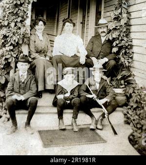 Photographie originale vintage d'une famille de 6 personnes assises sur leur porche avant, vers 1910, États-Unis. Banque D'Images