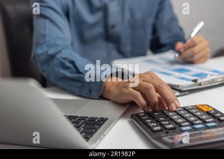 Homme d'affaires utilisant la calculatrice et les documents comptables au bureau avec ordinateur portable. Banque D'Images