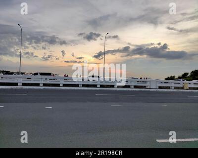Cette image de plein air capture un coucher de soleil à couper le souffle, vu à travers la clôture blanche d'une autoroute Banque D'Images
