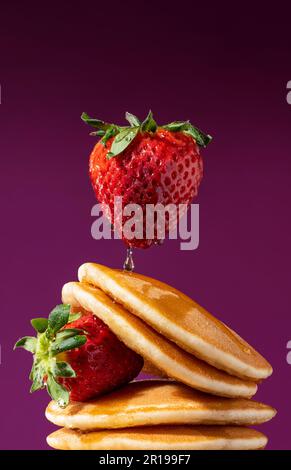 Faire levier à la fraise sur une pile de crêpes arrosées de miel. Plan conceptuel. Banque D'Images