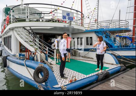 Le capitaine et le guide accueillent les passagers sur le bateau de croisière la Muse prêt à naviguer dans la baie de Bai Tu long dans l'archipel de la baie d'Halong, au Vietnam. Banque D'Images