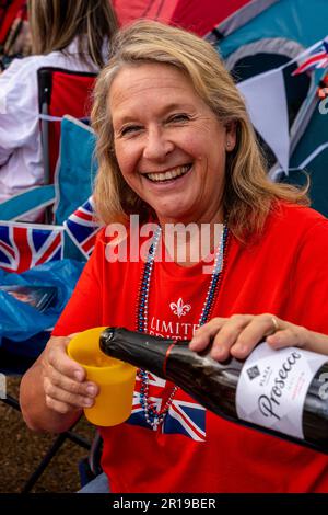 Une femme d'âge moyen buvant Un verre de Prosecco avant le couronnement du roi Charles III, The Mall, Londres, Royaume-Uni. Banque D'Images