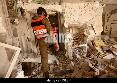 (230512) -- REHOVOT, 12 mai 2023 (Xinhua) -- le personnel de secours travaille à l'intérieur d'un appartement d'un immeuble résidentiel qui a été endommagé par une fusée lancée de Gaza, à Rehovot, en Israël, sur 12 mai 2023. Un homme israélien a été tué jeudi après-midi alors que des roquettes de Gaza frappaient un bâtiment résidentiel dans le sud d'Israël, après que deux commandants de roquettes palestiniens aient été tués par des frappes aériennes israéliennes plus tôt dans la journée. La fusée a frappé le deuxième étage d'un immeuble résidentiel de quatre étages à Rehovot, une ville située à 25 km au sud de tel Aviv, a déclaré les services d'incendie et de secours d'Israël. (Photo de Gil Co Banque D'Images