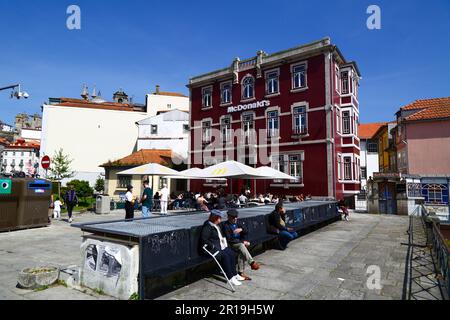 Personnes assises sur la place devant le point de vente de restauration rapide McDonald's sur Rua da Reboleira, quartier de Ribeira, Porto / Porto, Portugal Banque D'Images