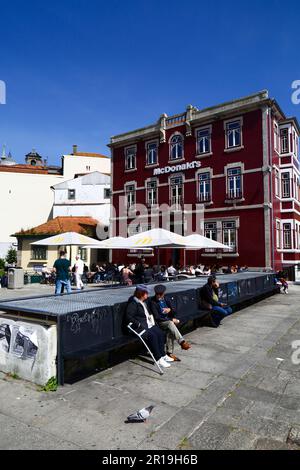 Personnes assises sur la place devant le point de vente de restauration rapide McDonald's sur Rua da Reboleira, quartier de Ribeira, Porto / Porto, Portugal Banque D'Images