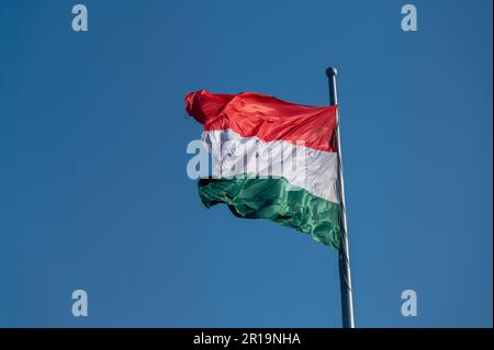 Drapeau national de la Hongrie volant d'un mât contre un ciel bleu Banque D'Images