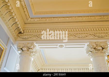 La texture du plafond en pierre blanche avec des motifs et de beaux moulures en plâtre et des colonnes anciennes. L'arrière-plan. Banque D'Images