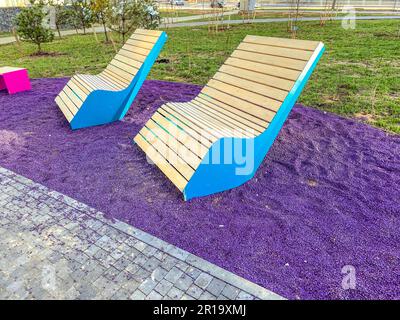 deux fauteuils en bois de petites planches sont disposés sur de petites pierres violettes. créer le confort dans la cour d'un immeuble résidentiel de plusieurs étages. mignon benc Banque D'Images