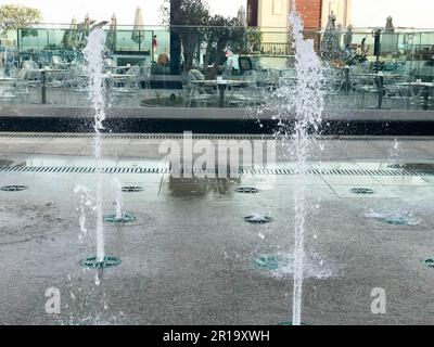 Une petite belle fontaine de chant en plein air, dans la rue. Gouttes d'eau, jets d'eau congelés dans l'air en vol sur fond d'un Banque D'Images