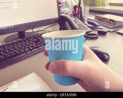 Tasse de café, clavier et ordinateur de bureau sur le bureau dans intérieur blanc de bureau à la maison. Photo réelle. Banque D'Images