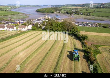 Timoleague, West Cork, Irlande. 12th mai 2023. Barry long, d'Eoin Coomey Agri & Plant LTD, balle de l'herbe pour John Michael Foley, agriculteur basé à Timoleague, en utilisant un tracteur New Holland T7,245 et une presse McHale Fusion 3 plus. Le village côtier de Timoleague et son estuaire sont illustrés en arrière-plan. Crédit : AG News/Alay Live News Banque D'Images