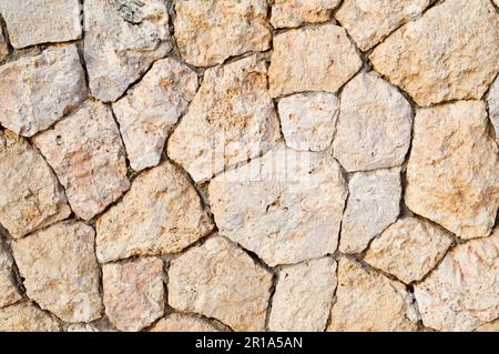 Texture d'un mur de pierre, routes de pierres, briques, pavés, tuiles avec des coutures de sable de gris ancien naturel jaune avec des bords tranchants. Le dos Banque D'Images