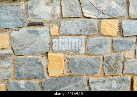 Texture d'un mur de pierre, routes de pierres, briques, pavés, tuiles avec des coutures de sable de gris ancien naturel jaune avec des bords tranchants. Le dos Banque D'Images