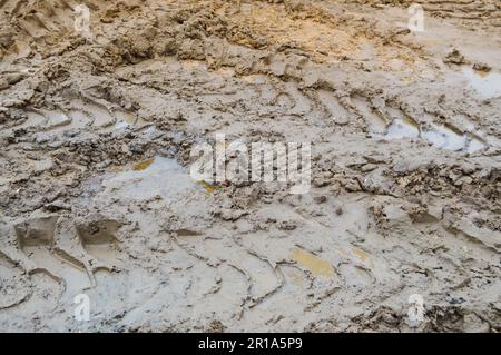 Texture d'une route sale de terre sale mauvaise route de terre avec des flaques et de l'argile sécher la boue avec des fissures et des ornières. Tout-terrain. L'arrière-plan. Banque D'Images