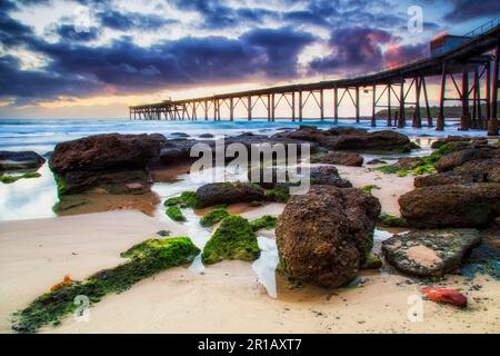 Des algues vertes ont couvert des roches de grès sur la plage du camp moyen de la baie de Catherine Hill, côte du pacifique, en Australie, au lever du soleil. Banque D'Images