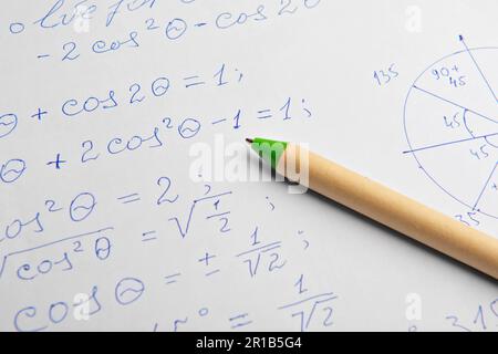 Papier avec calculs mathématiques écrits et stylo, gros plan Banque D'Images