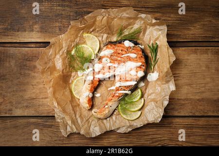 Savoureux steak de saumon avec sauce, tranches d'agrumes et herbes sur une table en bois, vue du dessus Banque D'Images