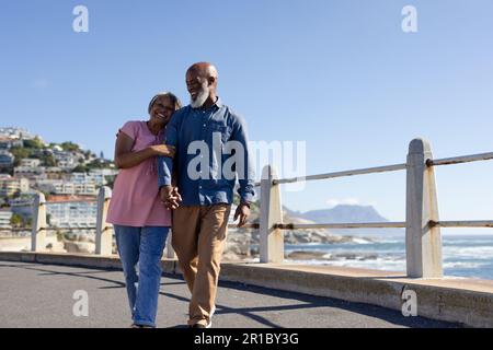 Heureux couple afro-américain senior marchant et embrassant sur la promenade au bord de la mer Banque D'Images