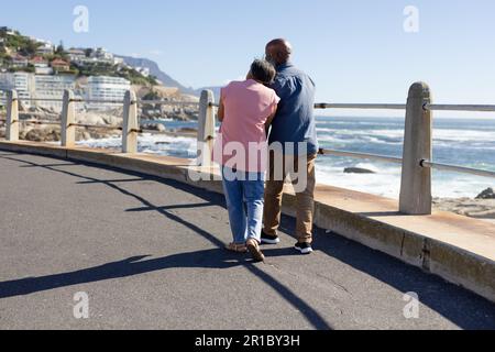 Heureux couple afro-américain senior marchant et embrassant sur la promenade au bord de la mer Banque D'Images