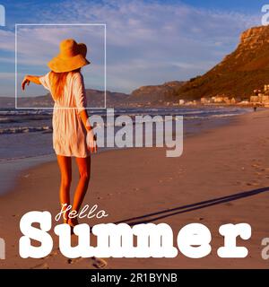 Composite de texte d'été Hello et insouciante jeune femme caucasienne portant un chapeau debout à la plage Banque D'Images