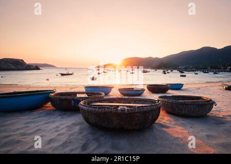 Paniers de bateaux sur la plage de sable dans la baie contre la mer au beau coucher du soleil. Village de pêcheurs sur les îles Cham au Vietnam. Banque D'Images