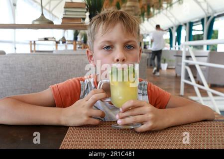 Un garçon goûtant de la limonade fraîche dans un restaurant Banque D'Images