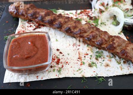 Agneau lula kebab avec rondelles d'oignon et sauce à bord dans le restaurant Banque D'Images