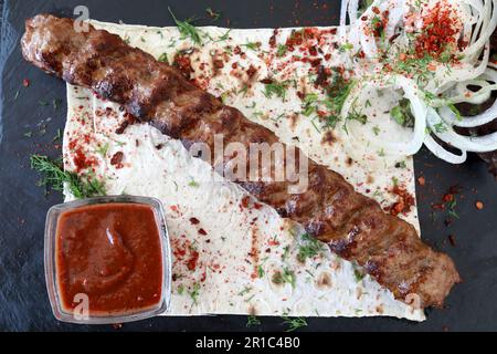 Lula kebab avec rondelles d'oignon et sauce à bord dans le restaurant Banque D'Images