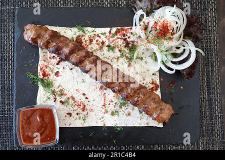 Lula kebab avec rondelles d'oignon à bord dans le restaurant Banque D'Images