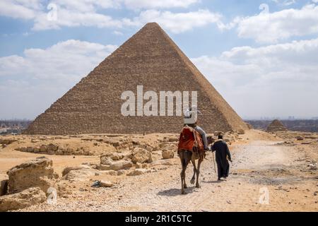 Touristes à cheval sur un chameau à côté des Pyramides de Gizeh au Caire, Egypte Banque D'Images