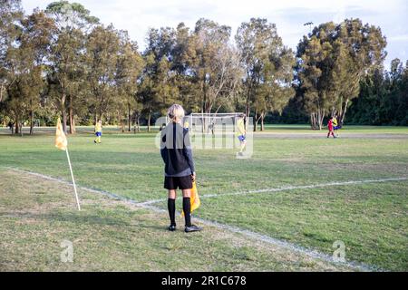 Football de base, jeune homme de ligne ou assistant d'arbitres courant la ligne à un match de football de mens, Sydney, NSW, Australie Banque D'Images