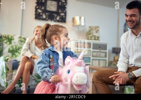 La jeune famille est capturée dans un moment de joie et de bonheur. La mère peut être vue rire en arrière-plan, tandis que le père se tient à côté de la Banque D'Images