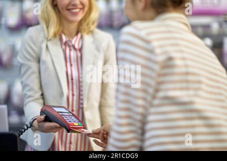 Un caissier souriant traite un paiement par carte de crédit pour un client dans un magasin. Banque D'Images