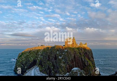 Château de Dunnottar perché sur les falaises conglomérat illuminées par la lumière du soir d'une journée froide de Winters en février. Banque D'Images