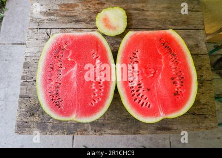 Pastèque vibrante déliez une demi-tranche rafraîchissante sur une table en bois - collation d'été de la ferme à la table pour manger sainement et manger un festin nutritif juteux Banque D'Images