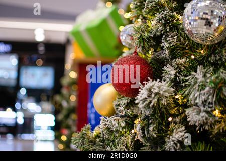 Gros plan de boules rouges de taille moyenne arbre de Noël décoré avec de petites ampoules est magnifique. Décoration d'arbre de Noël avec neige blanche, espace de copie sur la gauche pour des Banque D'Images