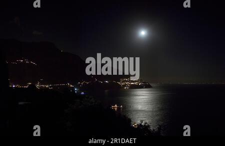 Vue de la côte nocturne de la mer illuminée par la lumière vive de la lune qui se reflète dans l'eau sombre Banque D'Images