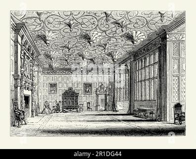 Une ancienne gravure de l'intérieur de la salle à dessin à Bramall Hall (Bramhall Hall), Bramhall, Greater Manchester, Cheshire, Angleterre, Royaume-Uni c. Le bâtiment est à ossature de bois Tudor – ses parties les plus anciennes datent du 14th siècle, avec des ajouts des 16th et 19th siècles. Le salon dispose d'une grande cheminée, de murs lambrissés et d'un plafond avec un impressionnant placoplâtre décoratif. Les grandes fenêtres laissent entrer beaucoup de lumière dans la pièce. Banque D'Images