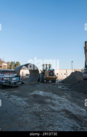 Un tracteur jaune et un morceau de tuyau de grand diamètre dans une zone de construction. Banque D'Images