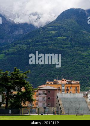 Une partie du stade de football Mario Puchoz et des propriétés résidentielles dans la ville d'Aoste, Vallée d'Aoste, NW Italie. Soutenu par des alpes enneigées Banque D'Images