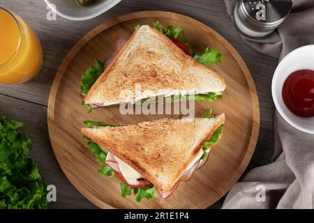 Un délicieux sandwich tranché avec du jambon, de la laitue fraîche et des tomates est servi sur une assiette. Vue de dessus. Banque D'Images