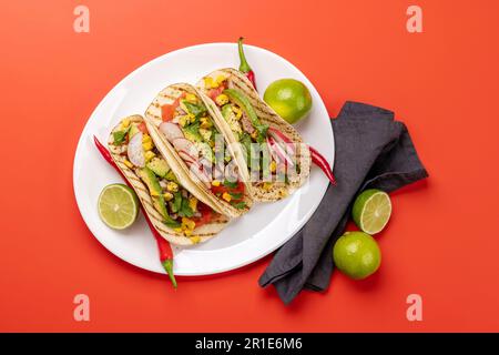 Cuisine mexicaine avec tacos à la viande et légumes grillés. Plat sur fond rouge Banque D'Images