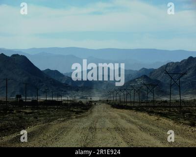 Route de terre menant vers les montagnes lointaines, accidentées et bleues de Richtersveld en Afrique du Sud, à travers le paysage désertique vide Banque D'Images